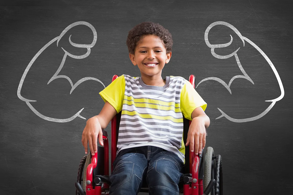 Image of boy in a wheelchair with a drawing of mussel arms on a chalk board